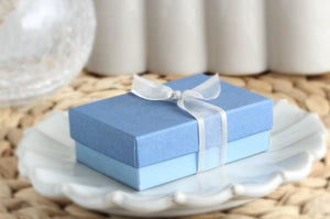 Two-tone dusty blue jewelry gift box tied with sheer white ribbon