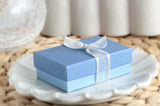 Two-tone dusty blue jewelry gift box tied with sheer white ribbon
